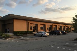 Separate shop doors at a highway strip center in late daylight — networking events in Pinellas Park
